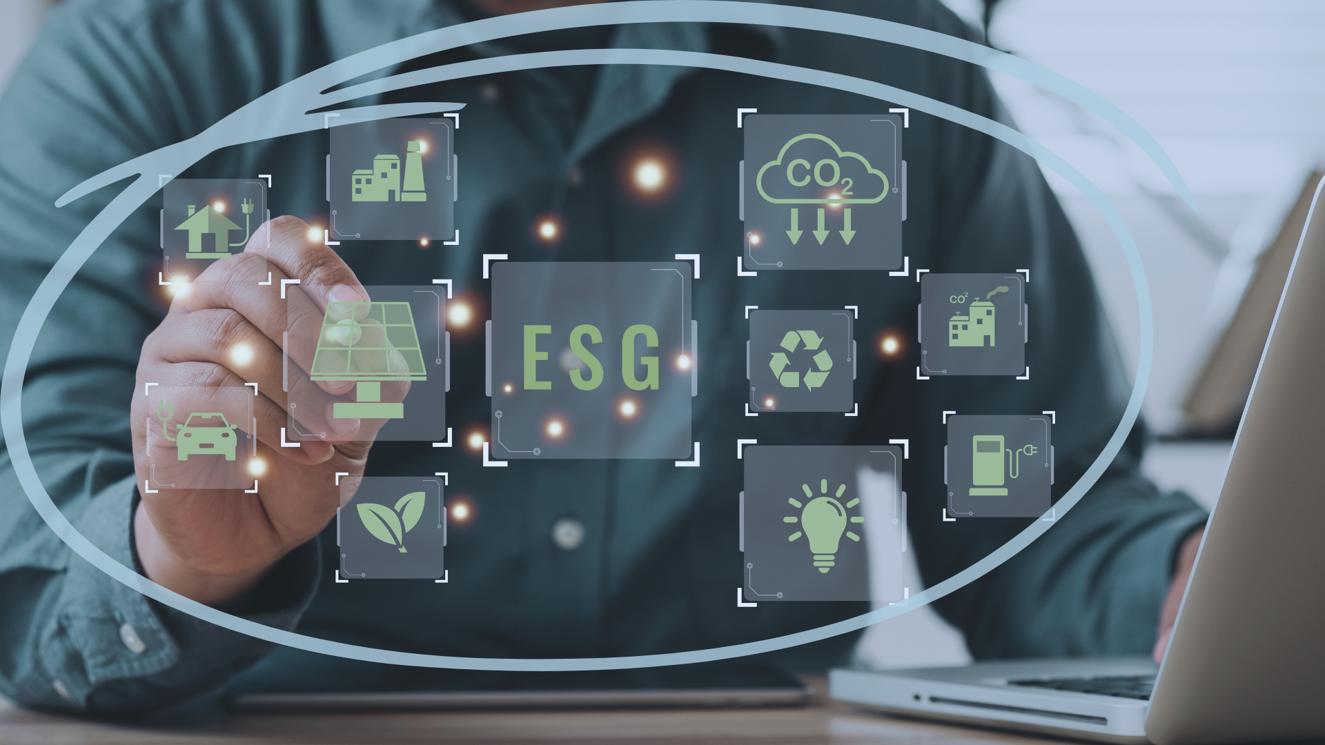 An image of a man in front of a laptop with ESG metrics at the center, surrounded by inputs affecting ESG.