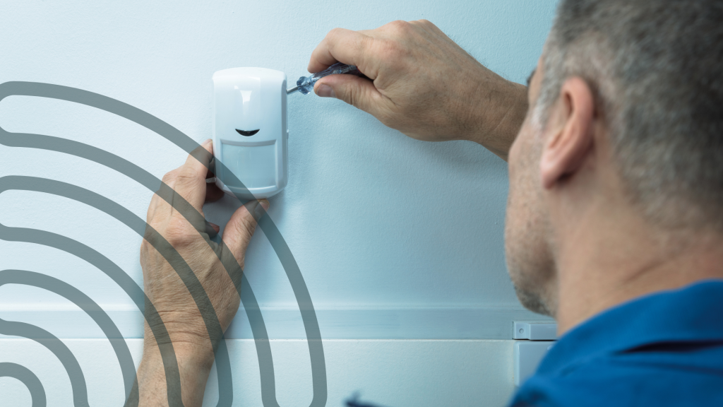 A handyman installing a smart building automation sensor on a wall