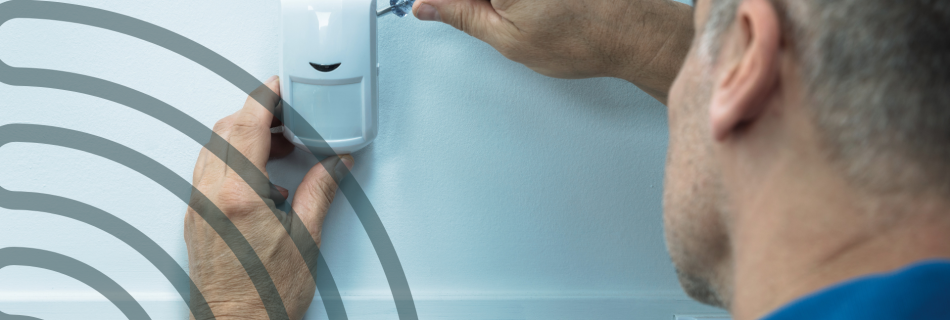 A handyman installing a smart building automation sensor on a wall