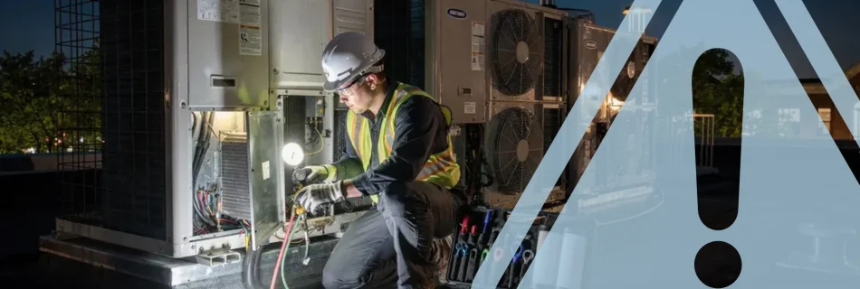 A technician working on a rooftop unit at night